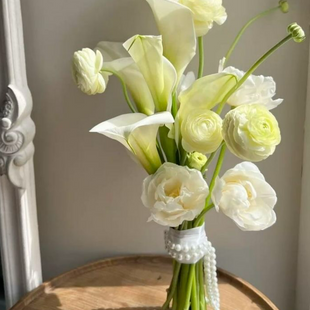 Bridal bouquet in white and green tones with calla lilies and ranunculuses